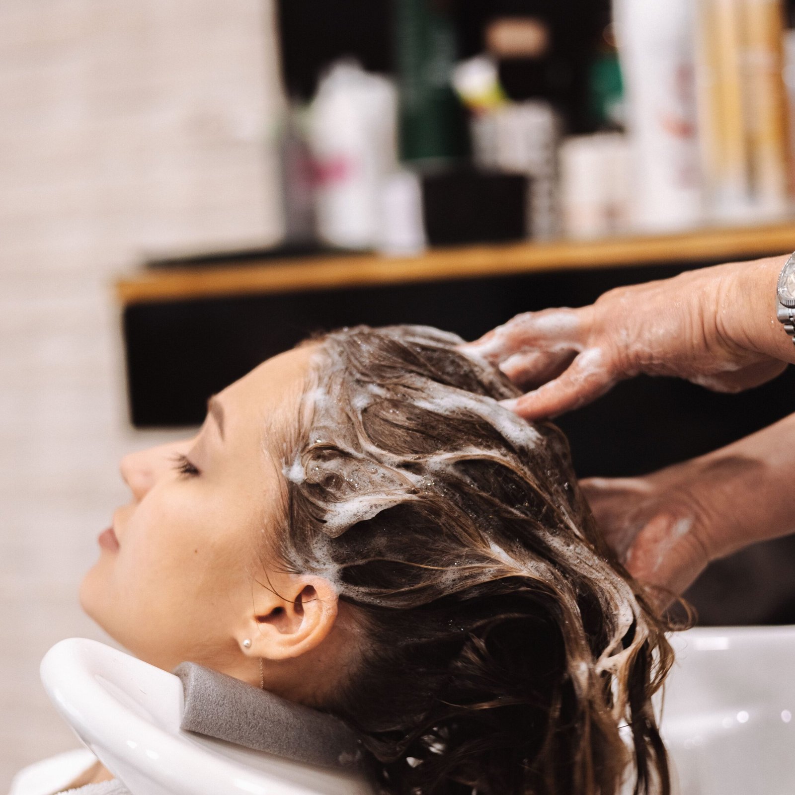 A woman enjoys a relaxing hair wash at a salon sink, showcasing a calm pampering moment.