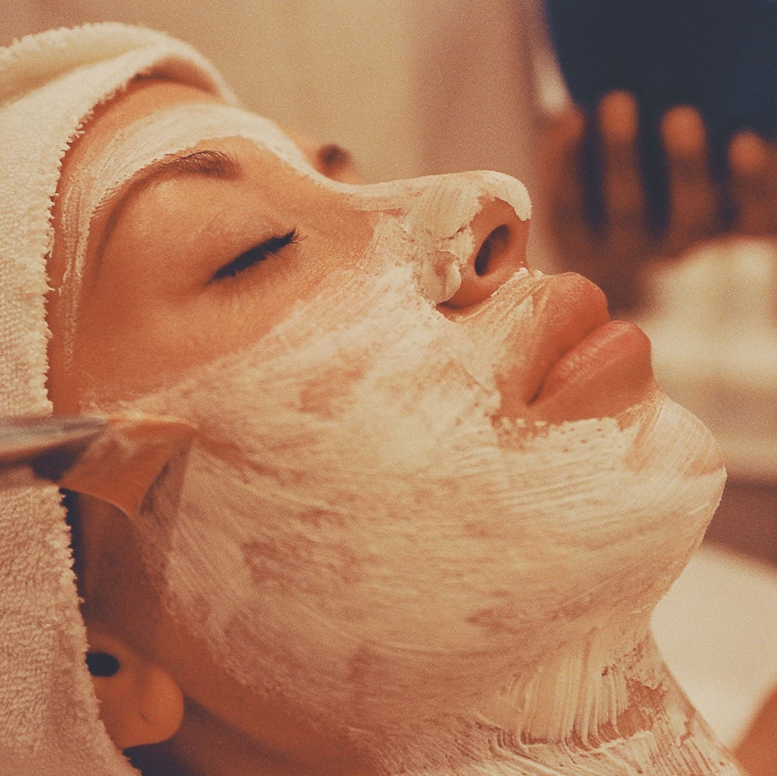 A calming spa facial treatment with a woman receiving a luxurious face mask application.
