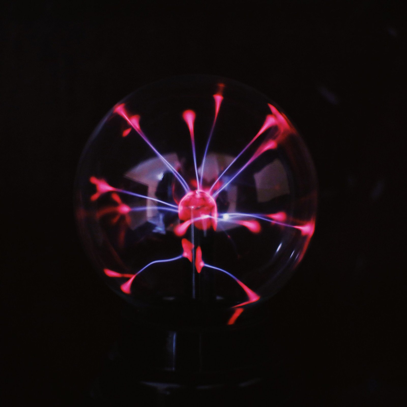Crystal glass plasma ball with glowing electric lights inside placed in dark room